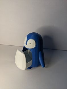 a blue and white elephant shaped object sitting on top of a gray table next to a wall