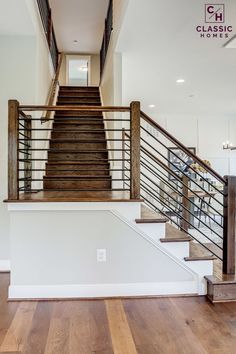 a stair case with glass railing and wood handrails in a home entryway