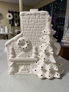 a white ceramic christmas tree next to a brick house shaped like a snowman's chimney