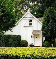 a white house surrounded by hedges and trees