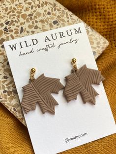 two brown leaf shaped earrings sitting on top of a card