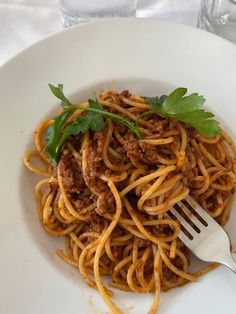 a white plate topped with spaghetti and meat