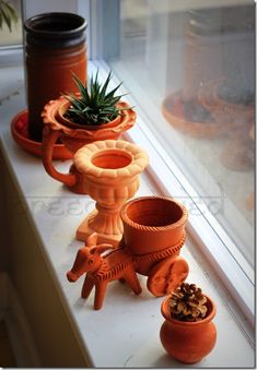 several clay pots are lined up on a window sill, with plants in them