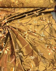 an image of a gold colored fabric with leaves on it and other things in the background