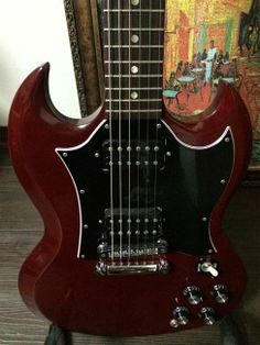 a red electric guitar sitting on top of a wooden floor