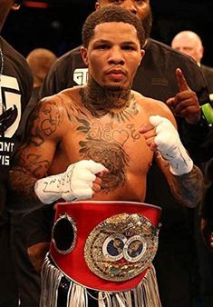 a man with tattoos on his chest standing next to another man in a boxing ring