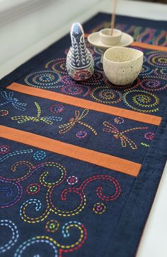 a blue table runner with an orange border and two bowls on it next to each other