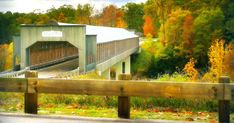 a wooden fence with a train going over it and trees in the backgroud