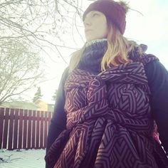 a woman standing outside in the snow wearing a scarf and hat with her hand on her hip