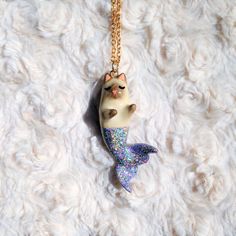 a necklace with a cat sitting on top of a mermaid tail