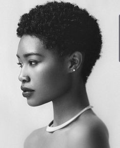 a black and white photo of a woman with an afro hairstyle, looking off to the side