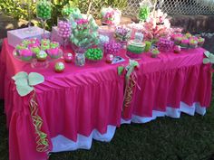 the table is covered with pink and green desserts