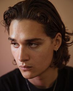 a close up of a person wearing a necklace and looking off to the side with a serious look on his face