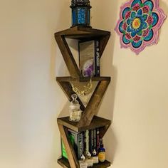 a corner shelf made out of wood with various items on it and a flower decoration hanging from the wall