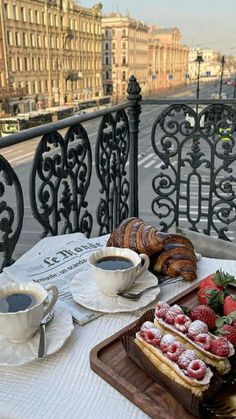 two trays filled with pastries on top of a table next to a cup of coffee