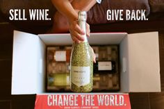 a person opening a wine bottle in a box with the words change the world written on it