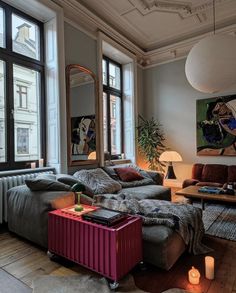 a living room filled with furniture next to windows and a painting hanging on the wall