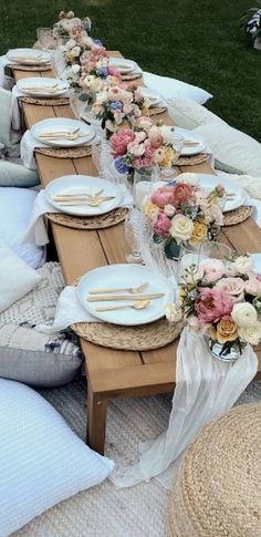 a long table set up with flowers and place settings for an outdoor dinner or bridal party