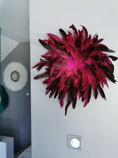 a large red flower mounted to the side of a white wall next to a mirror