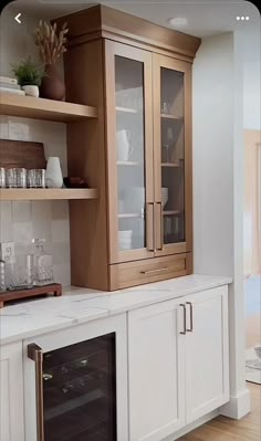 a kitchen with white cupboards and wooden shelves next to a wine glass rack on the wall