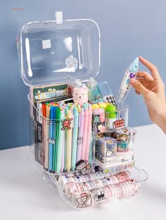 a clear plastic case filled with lots of different types of pens and pencils on top of a white table