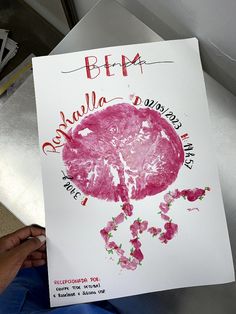 a child's hand holding up a poster with an image of a pink brain