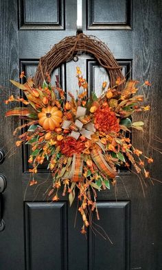 a wreath on the front door with pumpkins and other autumn decorations hanging from it