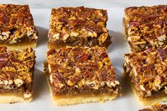 several pieces of pecan bar sitting on top of a white paper towel next to each other