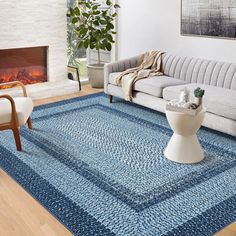 a living room filled with furniture and a blue rug on top of a hard wood floor