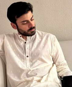 a man sitting on top of a white couch wearing a white shirt and black gloves