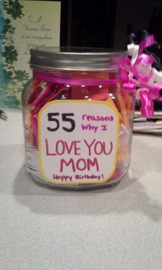 a jar filled with candy sitting on top of a table next to a pink ribbon