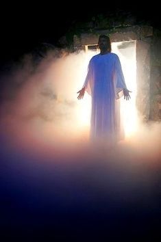 a man standing in the fog with his arms outstretched and hands out to the light coming from behind him