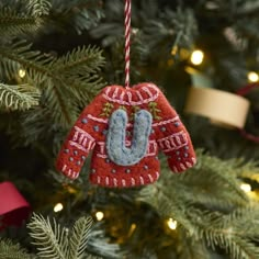 an ornament hanging from the christmas tree is decorated with a red sweater and blue booties