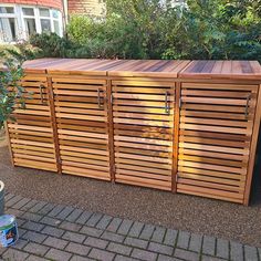 a large wooden cabinet sitting on top of a brick sidewalk next to a tree and bushes