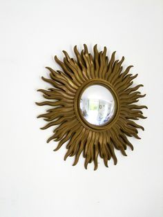 a mirror that is on the wall with a sunburst in front of it