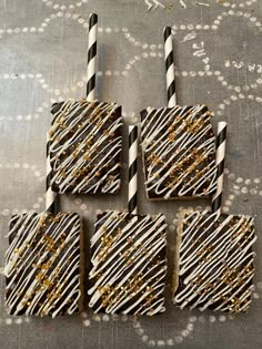 four decorated cookies with chocolate and gold sprinkles on a silver tablecloth