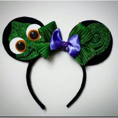 a green mickey mouse ears with eyes and a purple bow