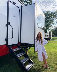 a woman standing next to a red and white trailer in the middle of a field