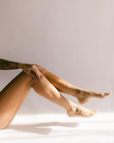 a woman is sitting on the floor with her legs crossed and tattoos on her arm