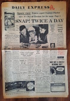 an old newspaper is laying on top of a wooden table next to another paper that says snap twice a day