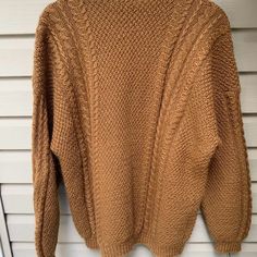 a brown sweater hanging on a white wall