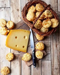 a basket filled with muffins next to a cheese wedge and some other pastries