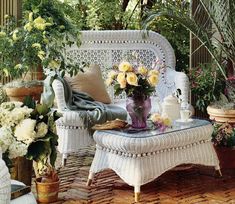 a white wicker couch sitting on top of a wooden floor next to potted plants