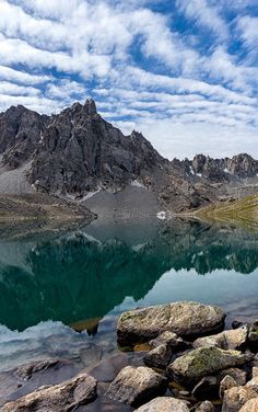 a mountain lake surrounded by rocks under a blue sky with some clouds in the background