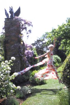 a woman in a dress is throwing a frisbee into the air with her arms