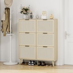 a white cabinet with shoes on it next to a hat rack and coat hanger