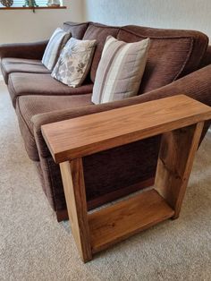 a wooden table sitting on top of a couch in a living room next to a window