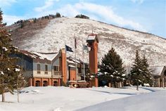 a large building on the side of a snow covered hill with trees in front of it