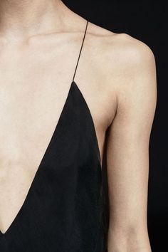 the back of a woman's black dress with her hands on her hips and one hand holding an object