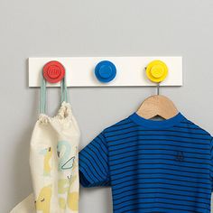 a blue shirt hanging on the wall next to a white bag and wooden pegs